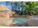 Unique rock-enclosed hot tub with small waterfall and a view of tropical plants and palm trees at 1117 Oxbridge Ln, Ormond Beach, FL 32174