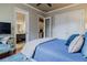 Bright main bedroom featuring a blue bed set, mirrored dresser, and adjacent bathroom at 1117 Oxbridge Ln, Ormond Beach, FL 32174