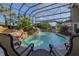 Enclosed pool area with rock waterfall, tropical landscaping, and comfortable seating for outdoor relaxation at 1117 Oxbridge Ln, Ormond Beach, FL 32174