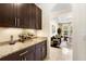 A Butler's pantry is featured with granite countertop, wine rack, cabinetry, and access to the living area at 115 San Marino Ln, Deland, FL 32724