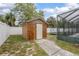 Backyard shed adjacent to screened in lanai with light wood paneling and white door at 1369 Saxon Blvd, Deltona, FL 32725