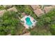 Aerial view of the community pool surrounded by trees and seating areas with an adjacent cabana at 140 Orchid Woods Ct # 14B, Deltona, FL 32725