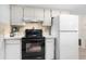 Compact kitchen features white cabinetry, black range, and a white refrigerator at 1426 Saxon Blvd, Deltona, FL 32725
