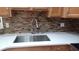 Close-up of a kitchen sink with a modern faucet, granite countertops, and tiled backsplash at 1491 E Palomar Dr, Deltona, FL 32738