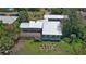 Rear aerial view of house with a stone foundation, metal roof, wooden deck, landscaped yard, and mature trees at 160 Rose Ave, Lake Helen, FL 32744