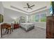 Relaxing bedroom featuring a tray ceiling, large windows offering natural light, and neutral gray decor at 173 Old Moss Cir, Deland, FL 32724