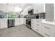Modern kitchen boasting white cabinets, stainless steel appliances, and gray wood-look tile flooring at 173 Old Moss Cir, Deland, FL 32724