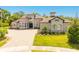 Elegant home featuring manicured lawn, brick driveway, turret entrance, and stone accents at 1855 Cattle Creek Ln, Port Orange, FL 32128