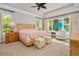 Bright primary bedroom showcasing tropical ceiling fan, stylish furniture, and natural light streaming through large windows at 1855 Cattle Creek Ln, Port Orange, FL 32128