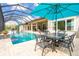 A screened-in pool area featuring a pool, dining table, and colorful umbrellas at 1855 Cattle Creek Ln, Port Orange, FL 32128