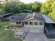 A two-story home with solar panels, a brick driveway, and ample covered parking at 1899 W Beresford Ave, Deland, FL 32720