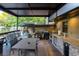 A covered outdoor kitchen features stone accents, a built-in grill, and ample counter space for cooking and entertaining at 1899 W Beresford Ave, Deland, FL 32720