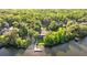 Aerial view of a lake front property with a tennis court, dock, and surrounded by trees at 2030 Waterford Estates Dr, New Smyrna Beach, FL 32168