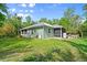 Green home exterior view showcasing the screened porches and landscaped backyard at 2030 Waterford Estates Dr, New Smyrna Beach, FL 32168