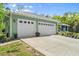 Large three-car garage shows white doors, metal roof, and landscaping, creating great curb appeal at 2030 Waterford Estates Dr, New Smyrna Beach, FL 32168