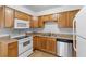 Functional kitchen with wood cabinetry, white appliances, and a practical layout for cooking at 211 S Delaware Ave, Deland, FL 32720