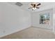 Bright bedroom features carpet, ceiling fan, a large window with trees beyond at 2704 Lancaster Ct, Apopka, FL 32703