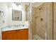 Bathroom featuring walk-in tiled shower, wood vanity with granite countertop, decorative mirror, and neutral wall color at 2982 S Atlantic Ave, New Smyrna Beach, FL 32169
