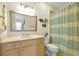 Bright bathroom with a single sink vanity, decorative mirror, and shower with a striped curtain at 2982 S Atlantic Ave, New Smyrna Beach, FL 32169