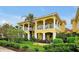 Beautiful yellow two-story condo with white pillars and balconies, set amidst lush landscaping and a blue sky at 2982 S Atlantic Ave, New Smyrna Beach, FL 32169