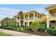 Attractive yellow two-story condo with white pillars and balconies, complemented by lush green landscaping at 2982 S Atlantic Ave, New Smyrna Beach, FL 32169