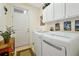 Well-organized laundry room with modern washer and dryer, overhead cabinets, and access to the home at 2982 S Atlantic Ave, New Smyrna Beach, FL 32169