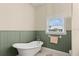 Elegant bathroom features a freestanding tub, wainscoting, and a window for natural light at 3310 John Anderson Dr, Ormond Beach, FL 32176