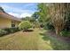 View of the home's backyard, showcasing the lawn, landscaping, and mature trees at 405 Secluded Oaks Trl, Deland, FL 32724
