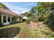 View of the home's backyard, showing the lawn, mature trees, and sunroom windows at 405 Secluded Oaks Trl, Deland, FL 32724