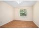 Bright bedroom featuring wood-look floors, a ceiling fan, and a window offering a lush green view at 405 Secluded Oaks Trl, Deland, FL 32724