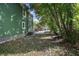A side view of the home's backyard showing the green siding, and the yard with mature trees and foliage at 415 W Church St, Deland, FL 32720