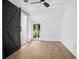Bright bedroom with wood-look floors, modern barn door, and a window offering a view of lush greenery at 415 W Church St, Deland, FL 32720
