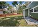 Green home's side view shows a fence, yard, and exterior features, all enhanced by mature landscaping at 415 W Church St, Deland, FL 32720