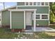 A front view of the front door of this green house, with white trim and white support columns at 415 W Church St, Deland, FL 32720