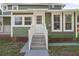 Charming green home featuring an inviting front entrance with stairs and a landing at 415 W Church St, Deland, FL 32720