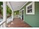 Inviting front porch features wood flooring, white railings, and a cozy seating area for relaxation at 415 W Church St, Deland, FL 32720