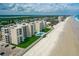 Beautiful aerial view of an oceanfront condominium building with a pool and manicured lawn next to a white sandy beach at 4505 S Atlantic Ave # 505, Ponce Inlet, FL 32127
