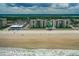 Expansive aerial view of beachfront condos, showcasing pristine beach access and community amenities, under a partly cloudy sky at 4505 S Atlantic Ave # 505, Ponce Inlet, FL 32127