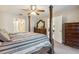 Bright bedroom featuring a four-poster bed, ceiling fan, and view to an en-suite bathroom at 481 W Holly Dr, Orange City, FL 32763
