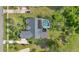 Aerial view of backyard featuring screened-in pool, well-manicured lawn, mature trees, and lush landscaping at 483 N Pine Meadow Dr, Debary, FL 32713