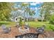 Landscaped backyard features a fire pit area with seating, surrounded by green grass and mature trees at 483 N Pine Meadow Dr, Debary, FL 32713