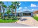 Charming waterfront home featuring a beautiful blue metal roof, lush landscaping, and a brick-paved driveway at 5 Talo Cir, Port Orange, FL 32127