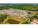 Aerial view of residential neighborhood with lush green surrounding and a water feature at 5064 Meadow Song Dr, Okahumpka, FL 34762
