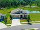 Single-Gathering home exterior boasts manicured landscaping, a two-car garage, and water view at 5064 Meadow Song Dr, Okahumpka, FL 34762