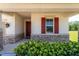 Close-up of front porch showcasing stone accents, a red door, and vibrant landscaping at 5064 Meadow Song Dr, Okahumpka, FL 34762