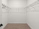 Empty walk-in closet features neutral colored carpet and metal shelving at 5064 Meadow Song Dr, Okahumpka, FL 34762