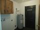 Utility room with an indoor water heater, cabinets, and dark door at 540 W Mathis Ave, Deland, FL 32720
