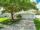 Charming single-story home featuring a well-manicured lawn, mature tree, and a two-car garage with driveway at 5479 Saint Regis Way, Port Orange, FL 32128