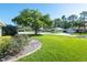 A lush front yard featuring a large shade tree, green grass, and colorful flower beds at 5479 Saint Regis Way, Port Orange, FL 32128
