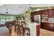 Open-concept kitchen featuring dark wood cabinets, granite countertops, stainless appliances, with bar and dining area at 5479 Saint Regis Way, Port Orange, FL 32128